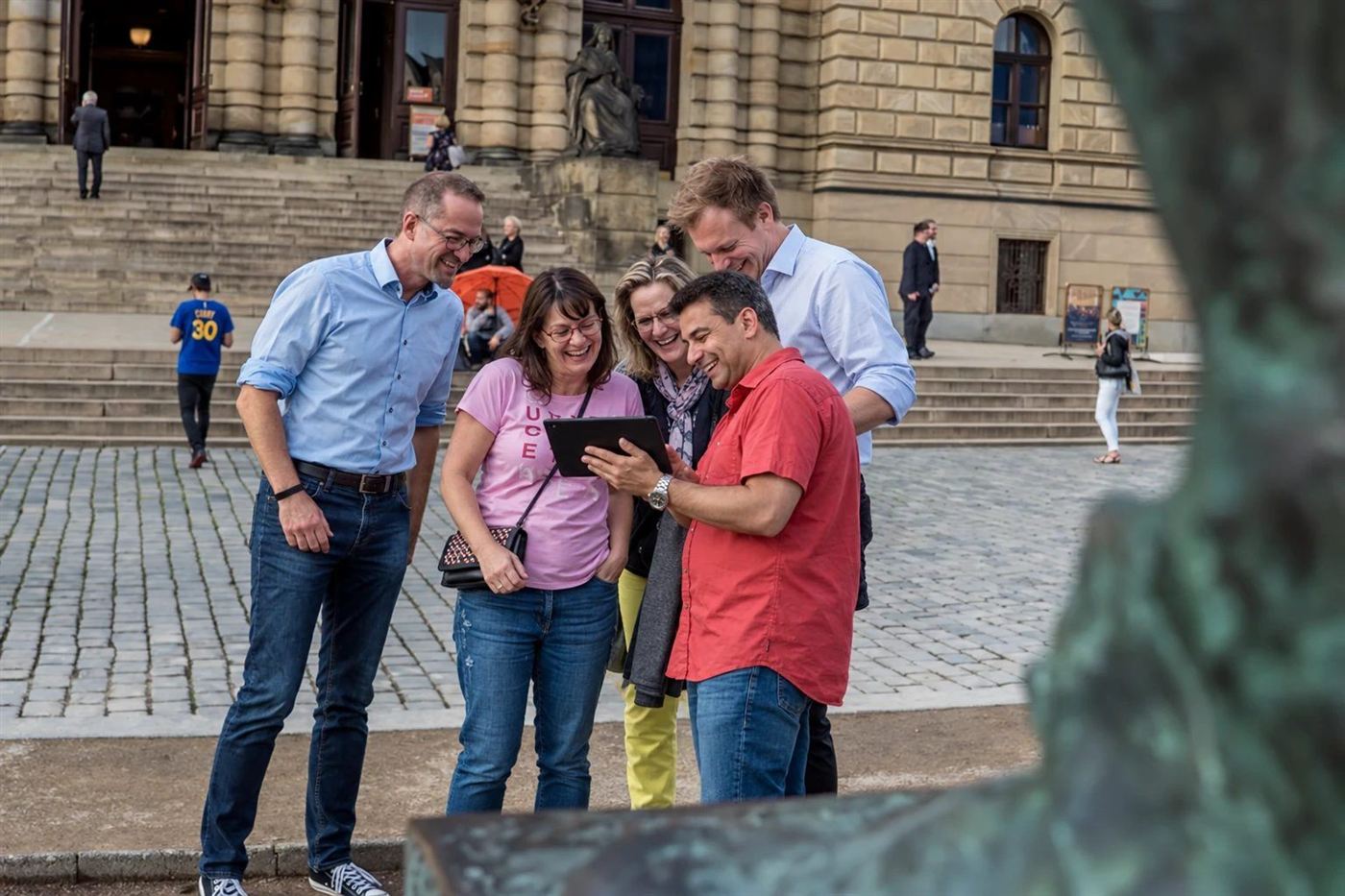 A team laughing over their tablet in front of the Rudolfinum