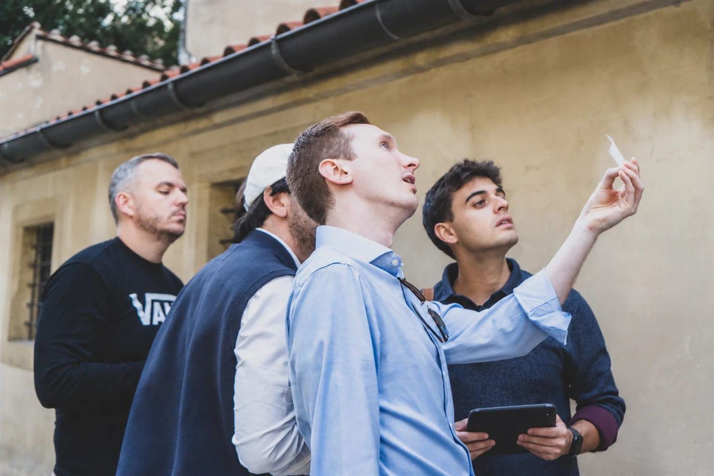 Players hold a clue up to the light by an old Old Town wall